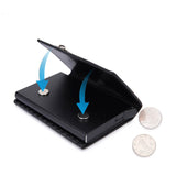 Le produit est mis de côté, à côté de deux pièces de monnaie, avec la partie ouverte qui se rabat sur les attaches magnétiques du produit.