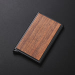 Porte cartes de crédit de luxe posé sur une table noir qui est fait avec du bois de noix et de un boîtier en alliage d'aluminium noir.