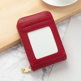 Porte carte en cuir rouge posé sur une table de marbre et adossé à un accessoire en bois.