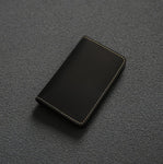 Porte cartes en cuir de vachette pleine fleur noir posé sur une surface noire.