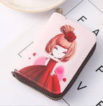 Porte carte de crédit en cuir rose clair avec une petite fille habillée avec une robe rouge dessus.