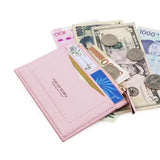 Le produit est mis sur une table blanche avec des cartes dedans ainsi que des billets et des pièces de monnaie éparpillés à côté du modèle.