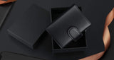Le porte-cartes est dans une boîte à cadeau noire qui est posée sur une table noire.