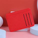 Porte carte bancaire en cuir rouge pour femme posé sur un accessoire blanc.