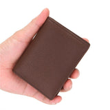 Un homme tient dans sa main gauche un porte-cartes de crédit en cuir.