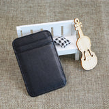 Le porte-cartes est adossé à un banc blanc miniature et à côté d'un violon en bois miniature