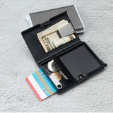 On voit l'intérieur du porte-cartes métallique avec des pièces de monnaie, des billets et des cartes dedans.