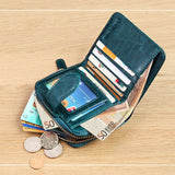 Posé sur une table marron, le porte-cartes en cuir pour femme est ouvert et remplie de billets, de pièces de monnaie et de cartes 