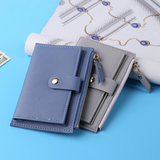 Deux porte-cartes en cuir sont posés sur un rouleau de tapisserie, lui-même posé sur une table avec une nappe bleue.