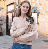 Une femme de face tient dans sa main un porte-cartes avec un airtag.