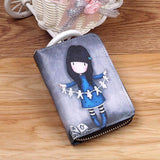Le porte-cartes est posé sur une table avec comme couverture une enveloppe en cuir sur lequel est dessiné une jeune fille en tenue bleue qui tient des bouts de papiers.