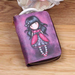 Le porte-cartes, posé sur une table en bois, a une couverture avec une jeune fille en tenue rouge dessinée dessus.